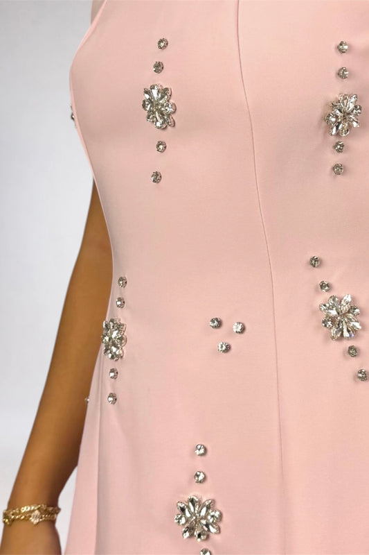 Close-up of a light pink sleeveless dress with silver rhinestone floral embellishments and small rhinestone accents on the bodice, worn by a model.