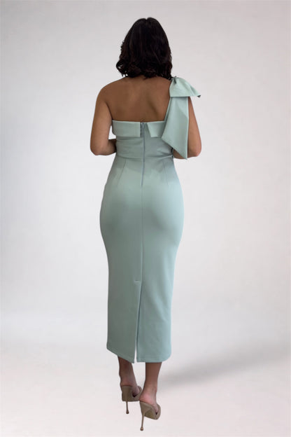 Woman wearing a light blue one-shoulder dress with a bow detail on a white background
