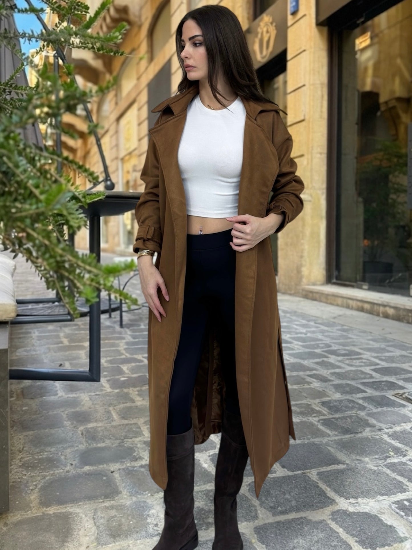 Woman wearing a brown coat and white top on a street.