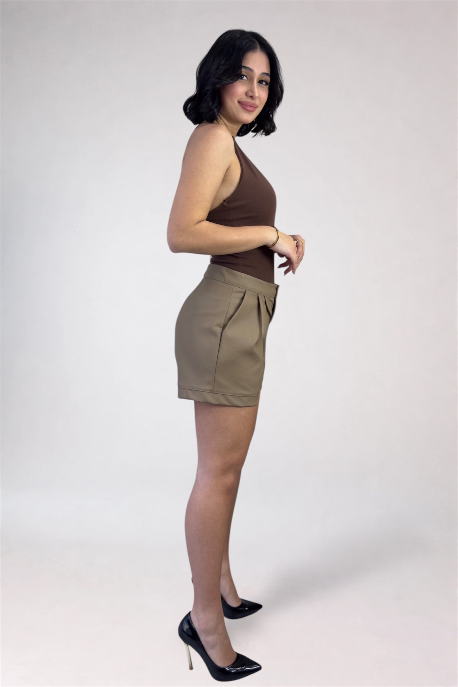 Woman wearing a brown top and beige shorts on a white background