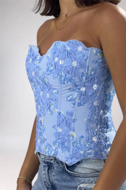 Blue floral top worn by a person on a plain background