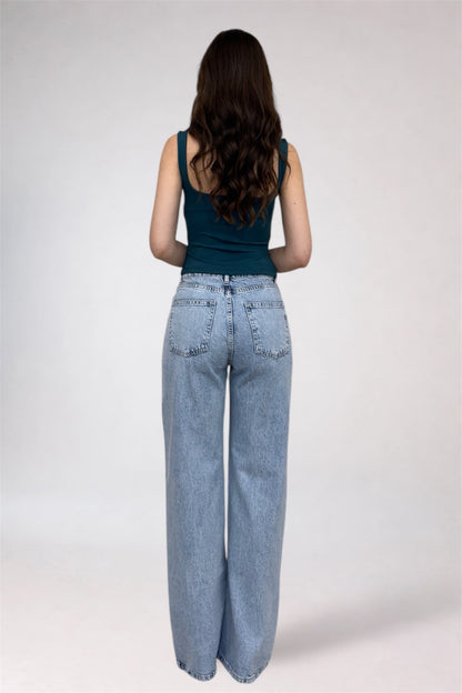 Person wearing light blue jeans and a dark green top on a white background