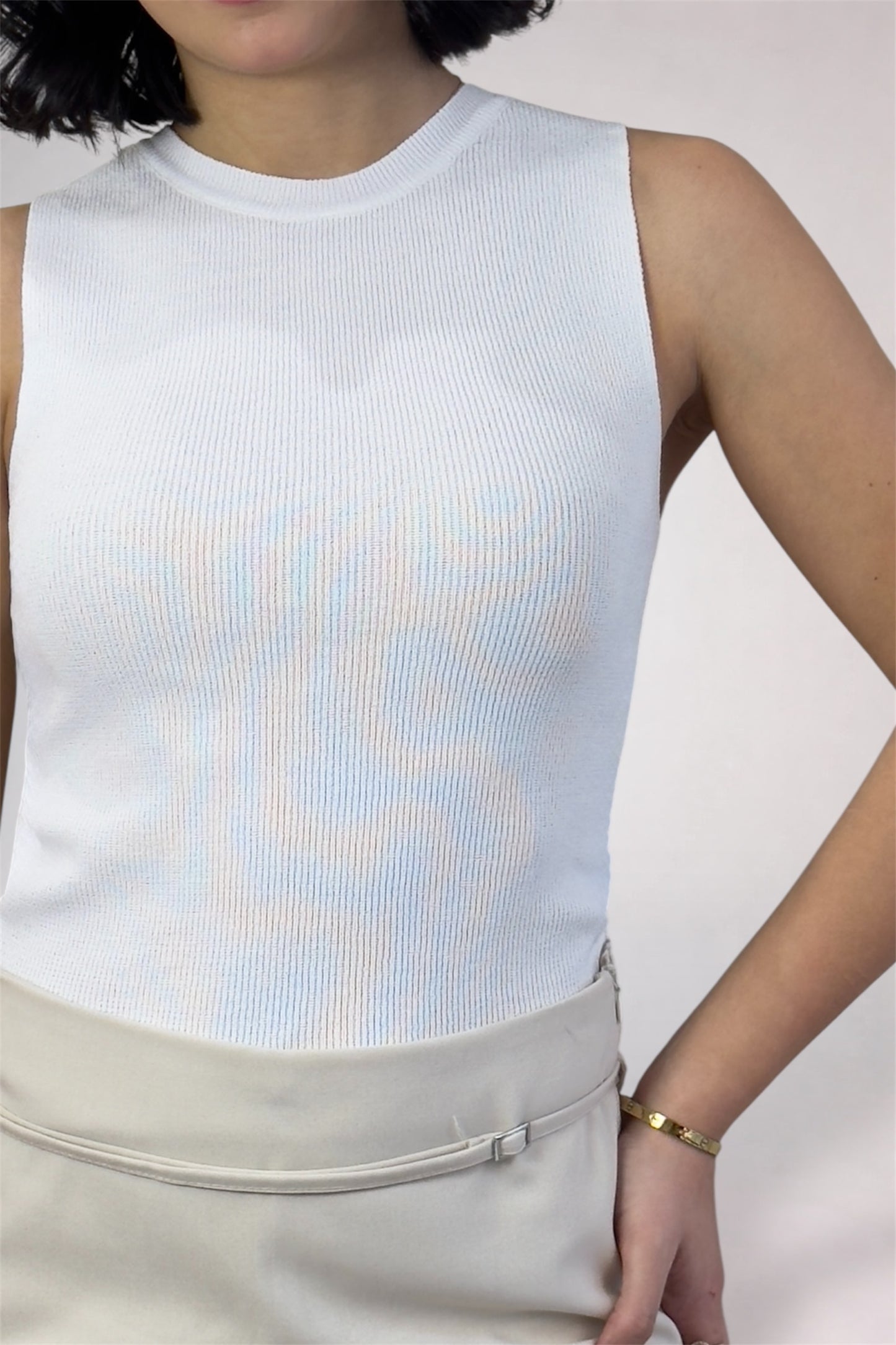 Person wearing a light blue sleeveless top with a white background