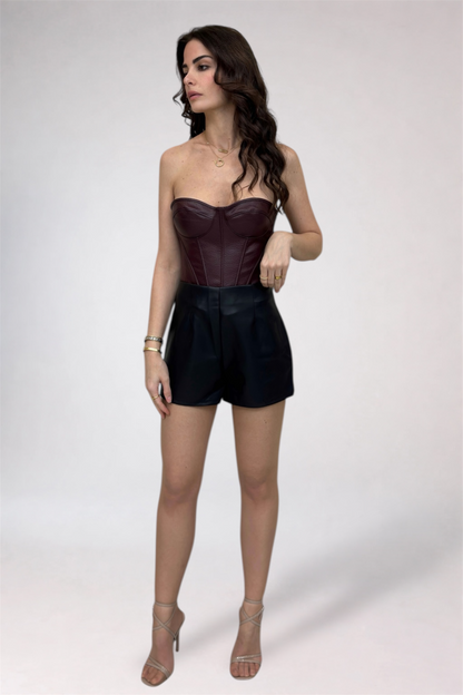 Woman wearing a strapless leather top and black shorts on a white background