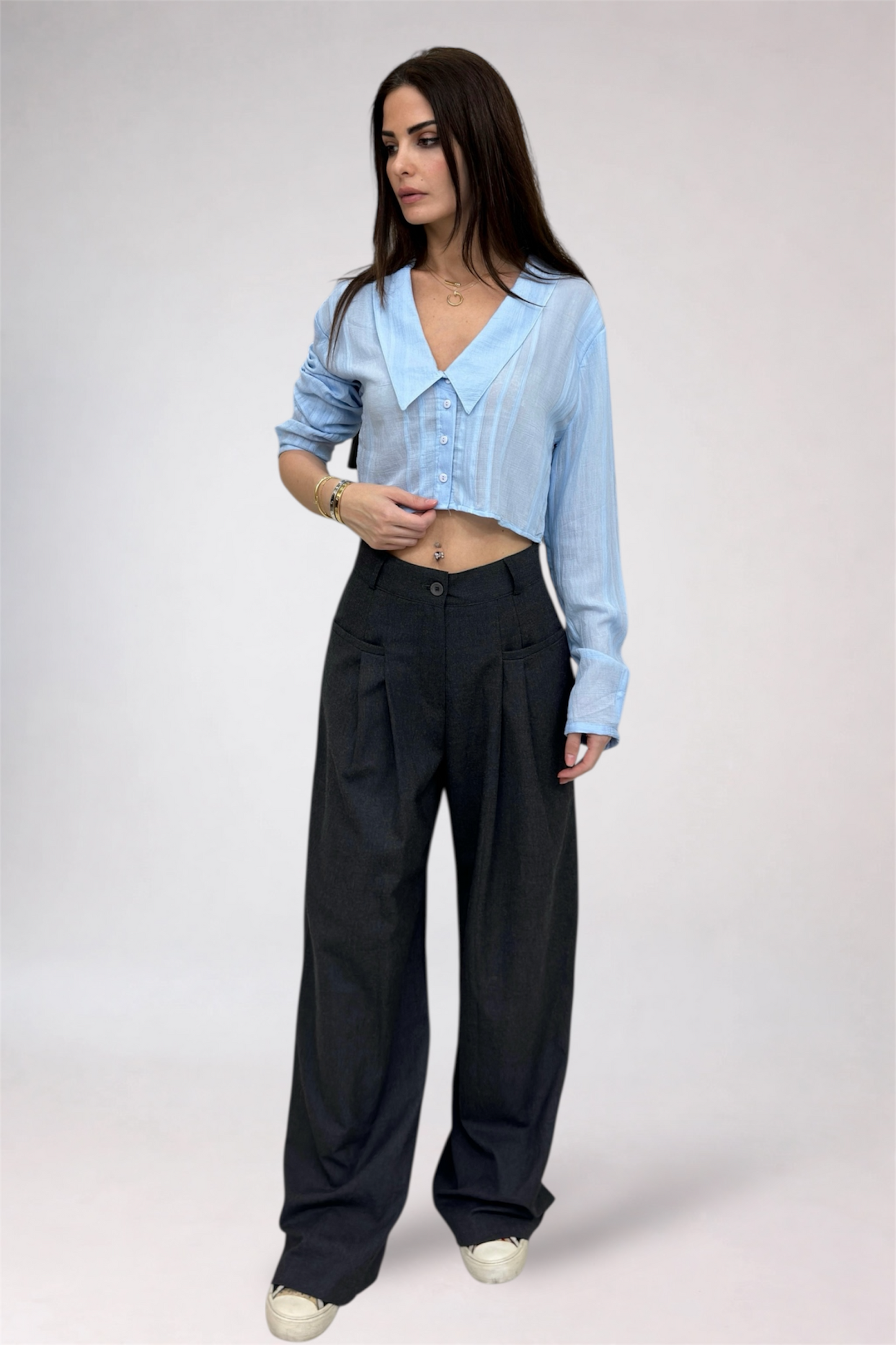 Woman wearing a light blue shirt and dark pants on a white background