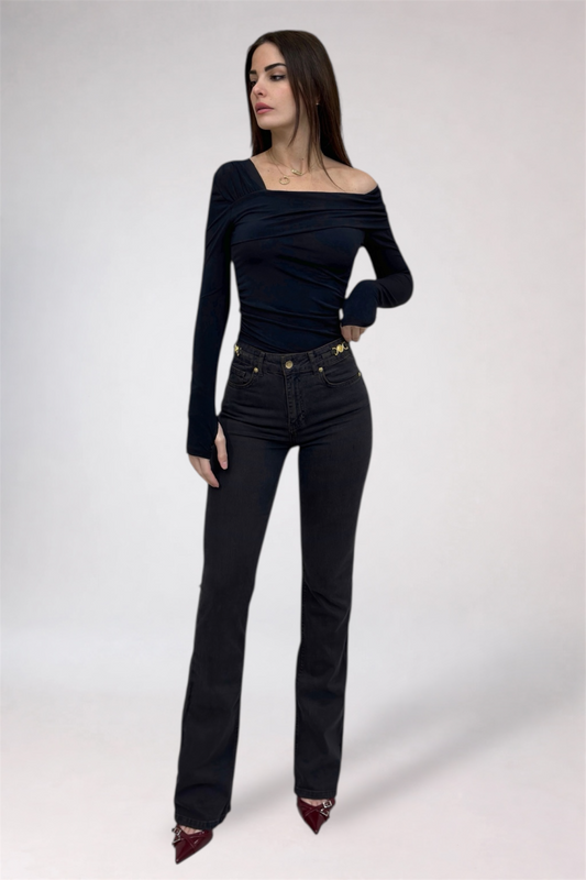 Woman wearing a black off-shoulder top and black jeans on a white background