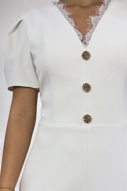 White outfit with gold buttons and lace details on a plain background
