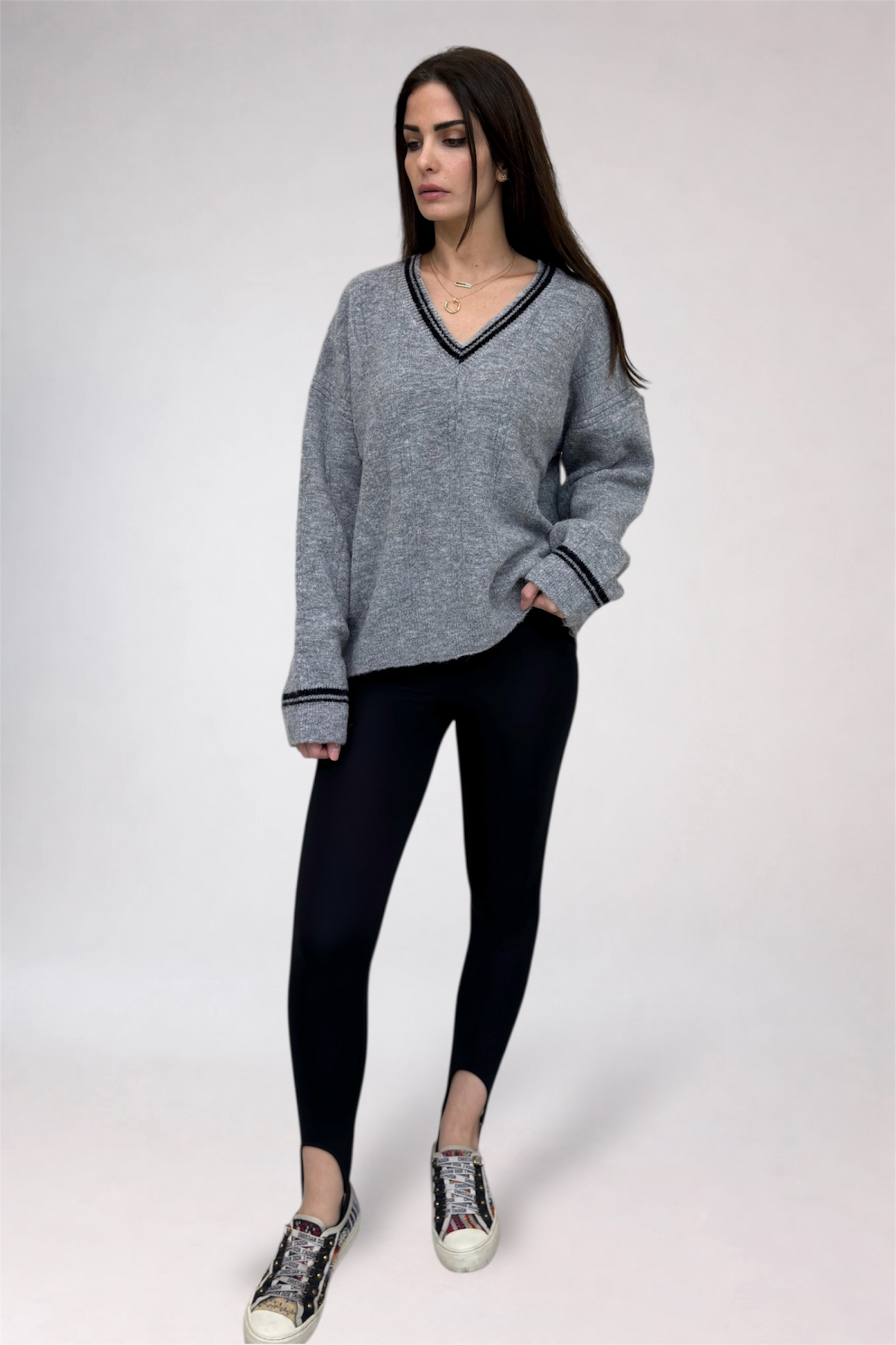 Woman wearing a gray sweater and black leggings on a white background