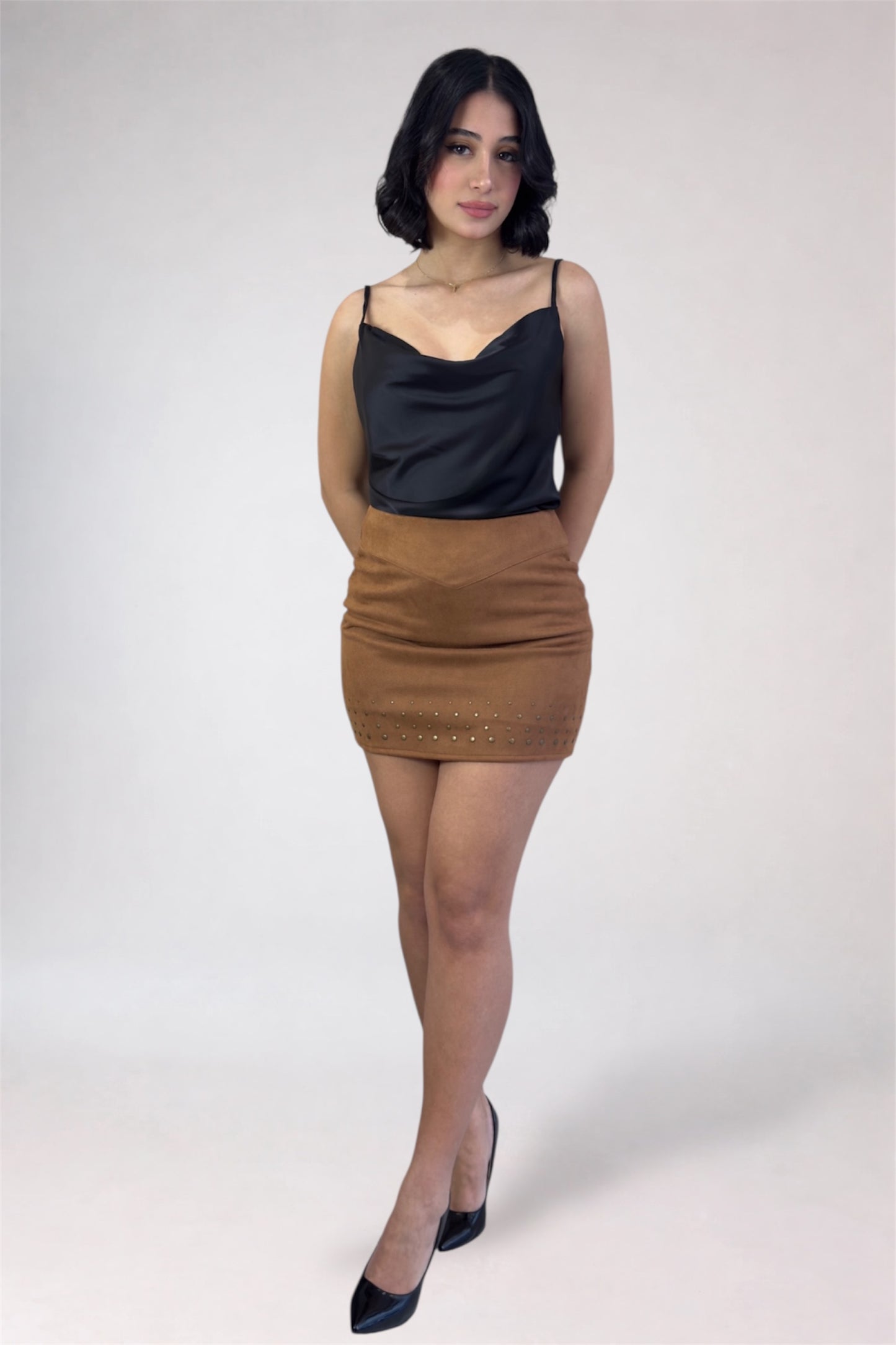 Woman wearing a black top and brown skirt on a white background