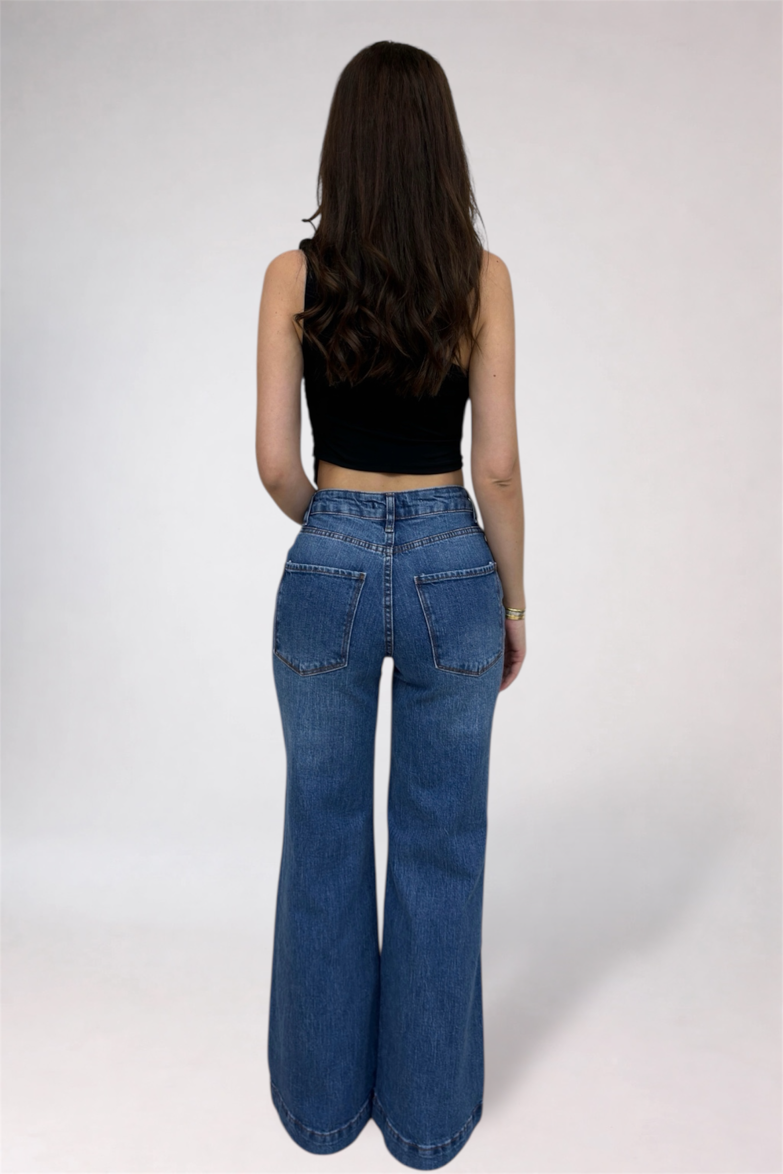 Person wearing blue jeans and a black top on a white background