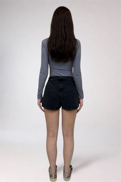 Person wearing a gray long-sleeve top and black shorts on a white background