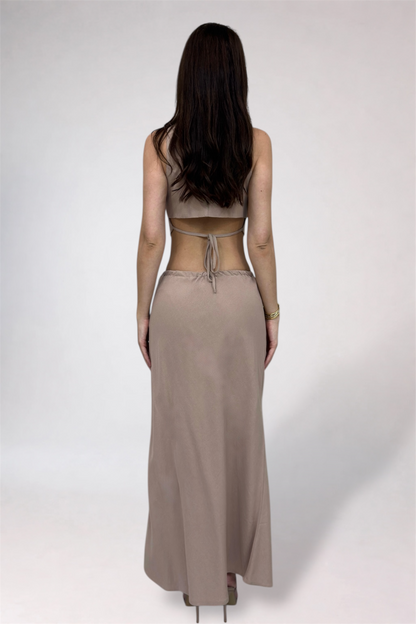 Person wearing a beige long skirt and top on a white background