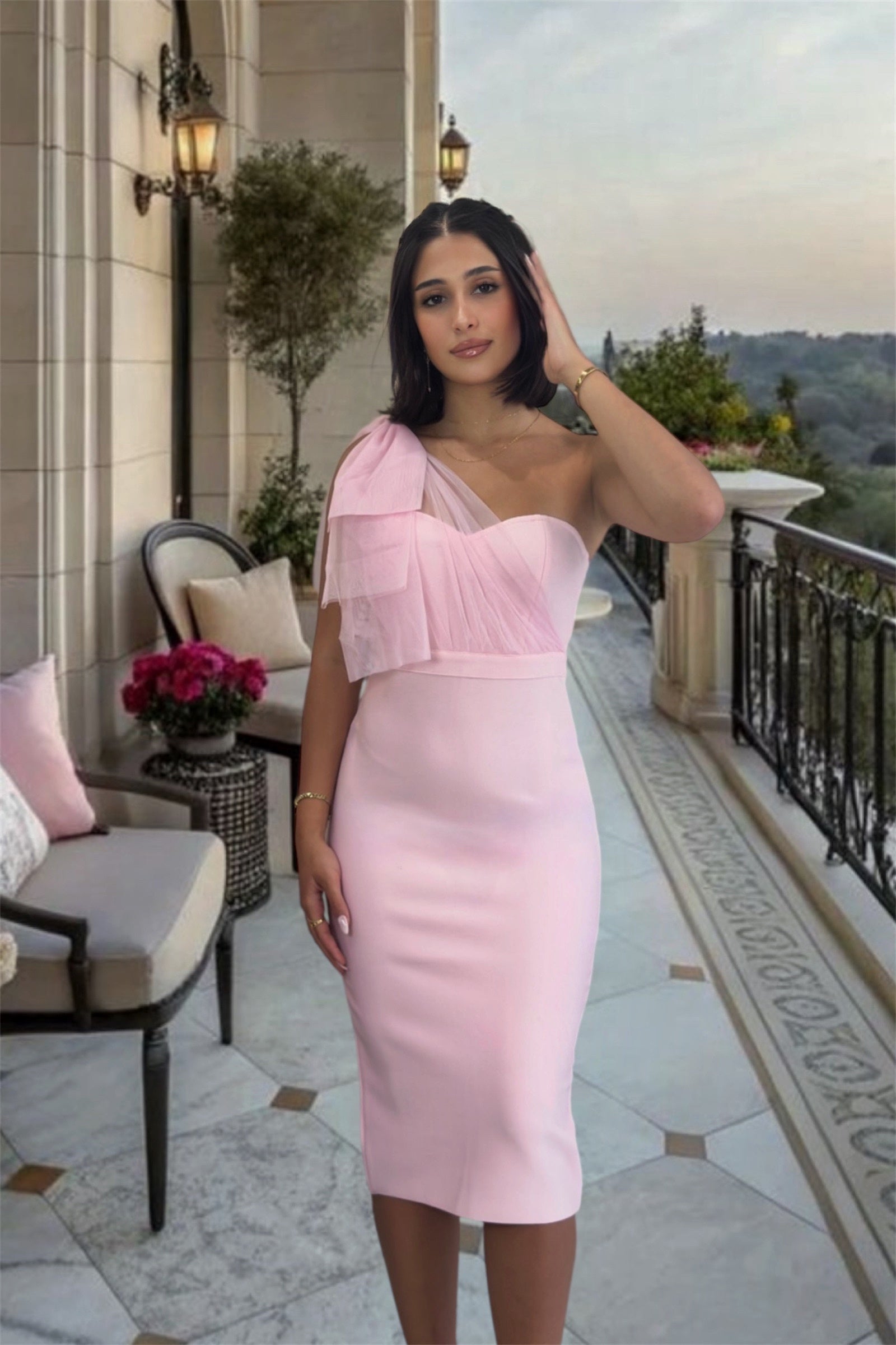 Woman in a pink dress standing on a balcony with scenic view