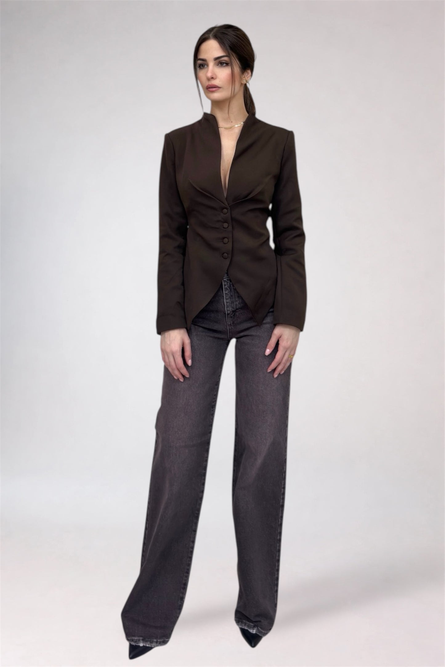 Woman wearing a brown blazer and gray pants on a white background