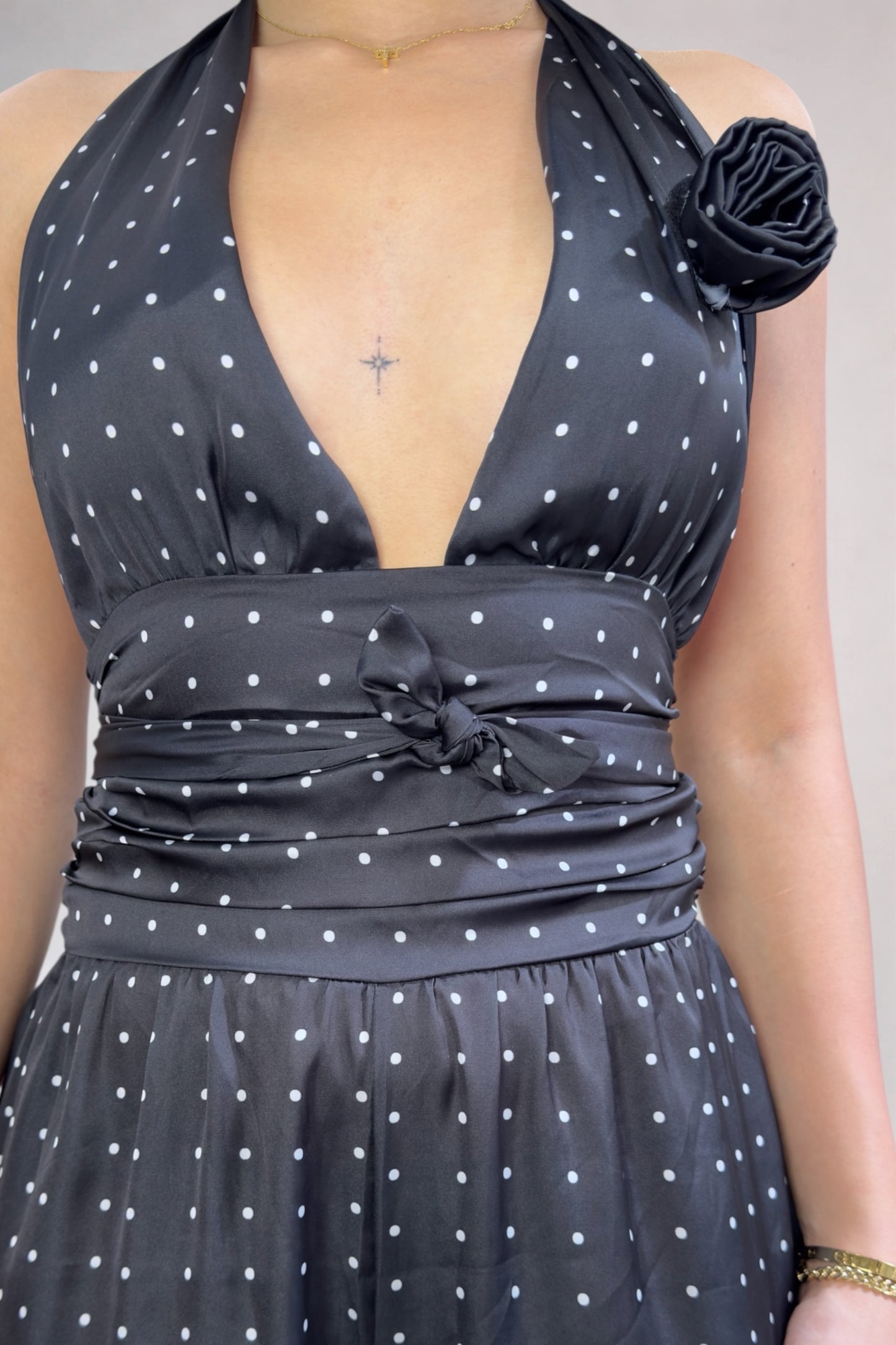Black polka dot dress with a floral detail on a neutral background