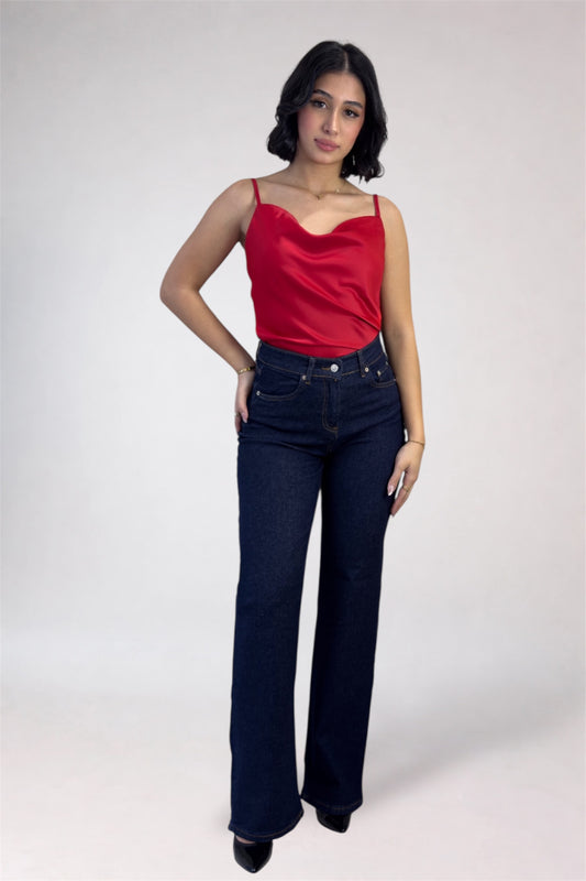 Woman wearing a red top and dark blue jeans on a white background