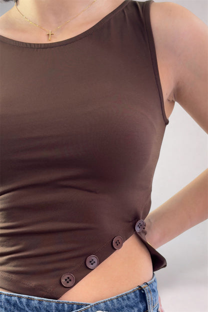 Brown sleeveless top with button details worn by a person on a plain background