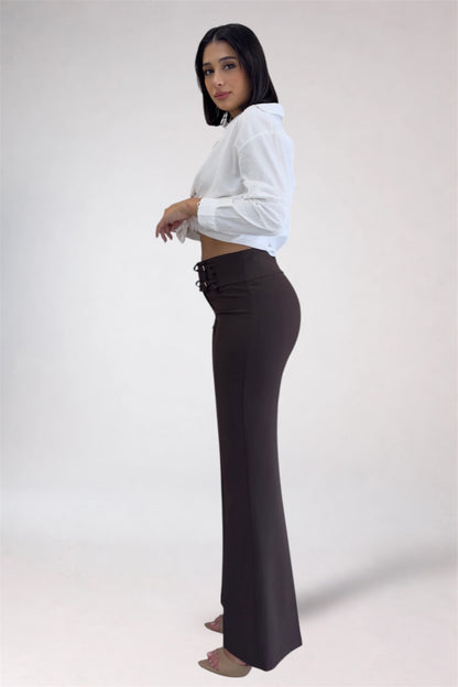 Woman wearing a white blouse and dark high-waisted pants on a white background