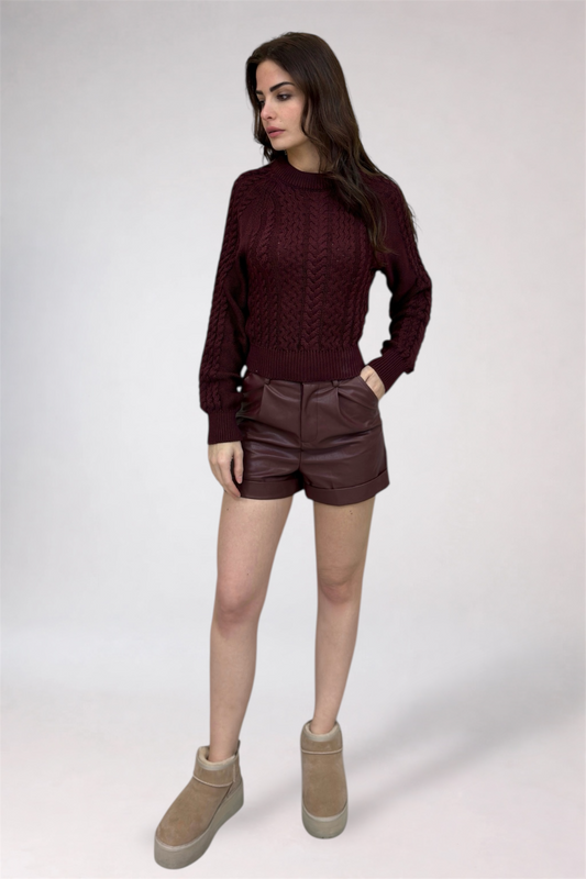 Woman wearing a burgundy sweater, brown shorts, and beige boots on a white background