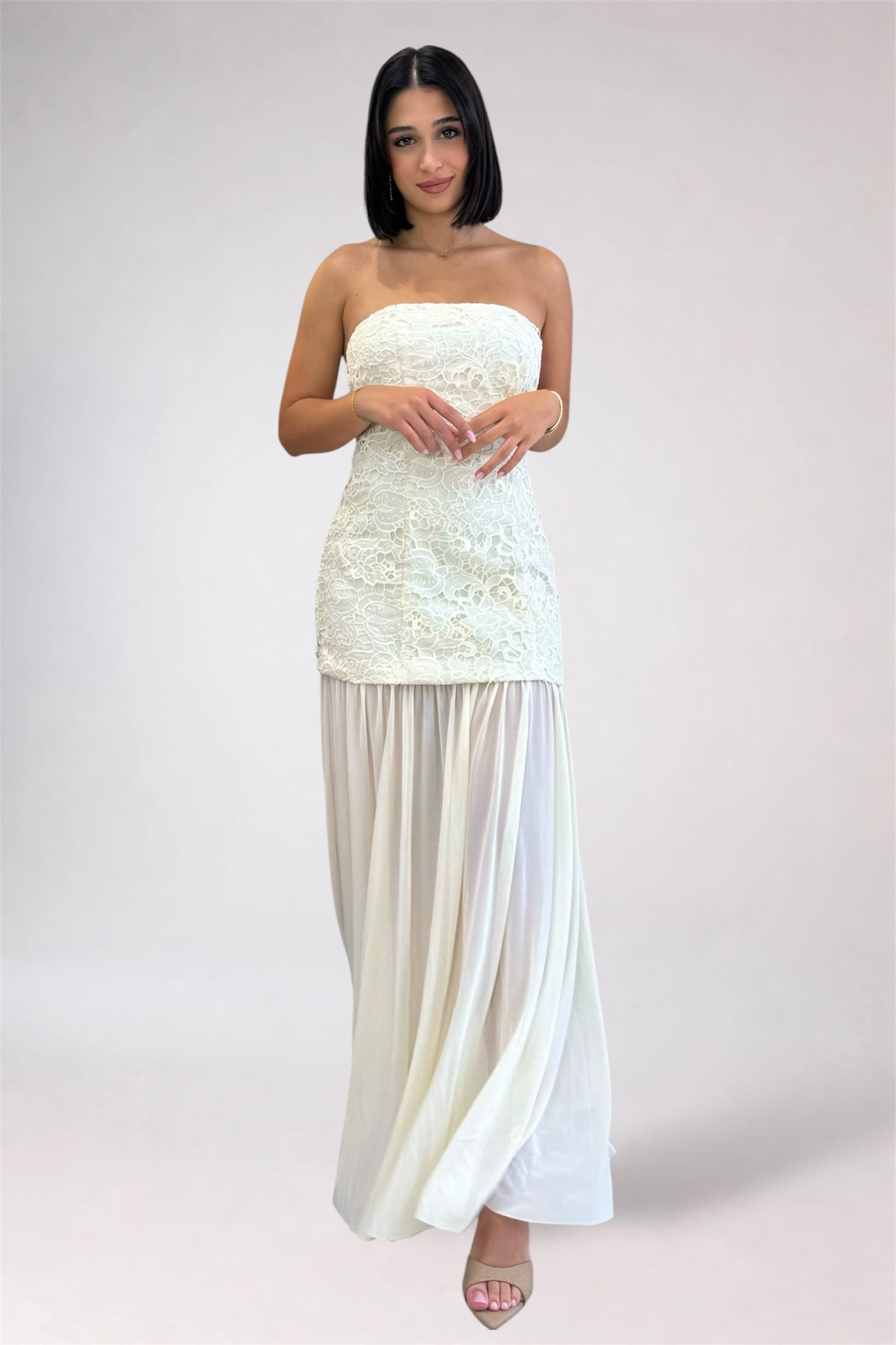 Woman wearing a strapless white dress with a plain background