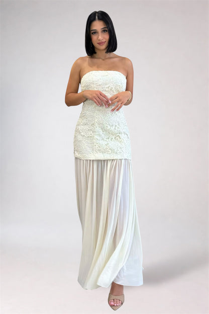 Woman wearing a strapless white dress with a plain background