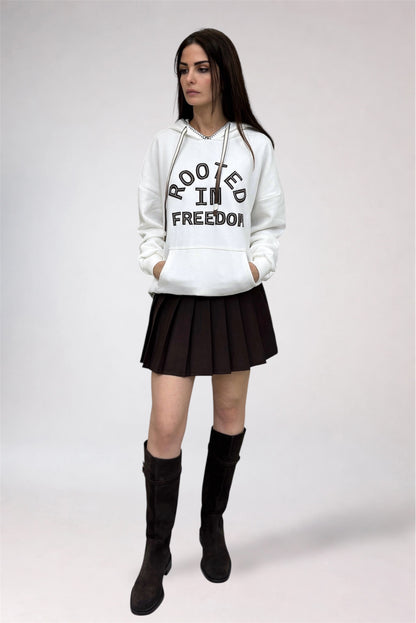 Person wearing a white hoodie with text, black skirt, and black boots on a white background