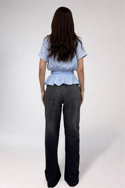 Person wearing a light blue top and dark gray pants on a white background