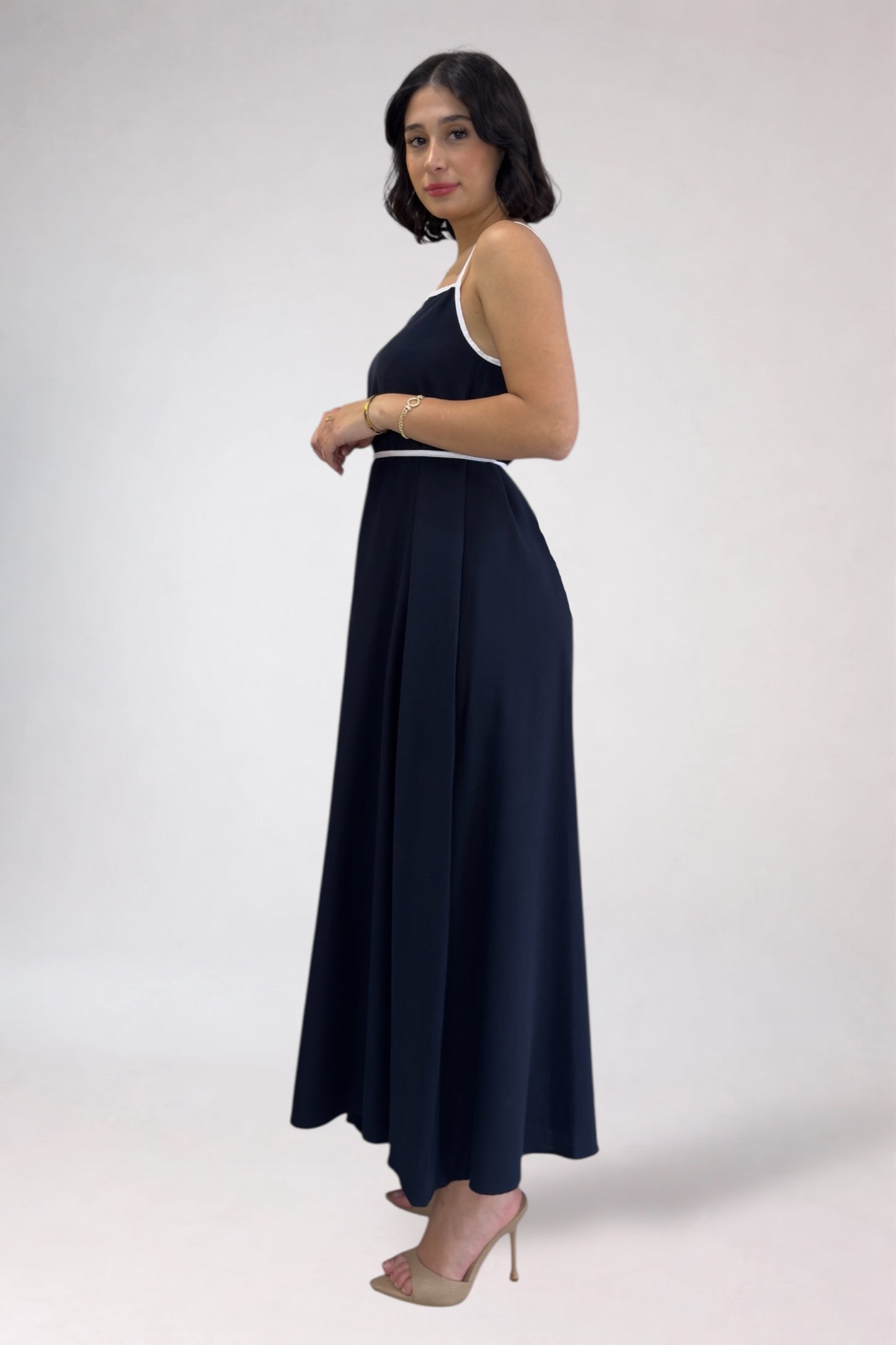 Woman wearing a navy blue dress with white trim on a white background