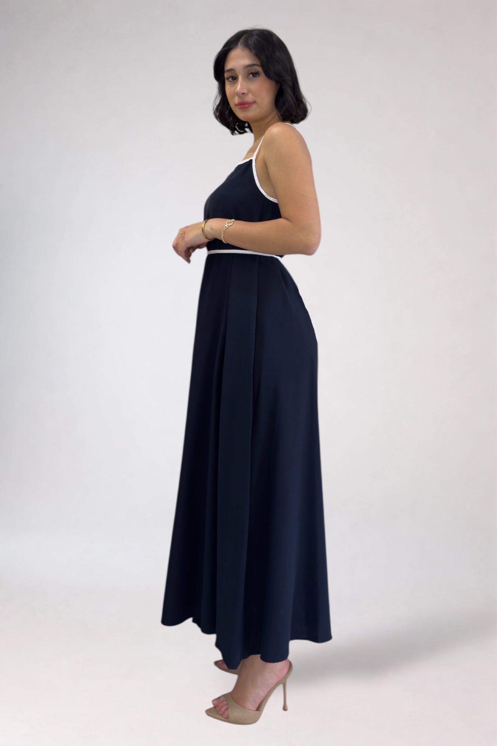 Woman wearing a navy blue dress with white trim on a white background