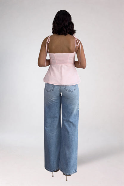 Person wearing a pink top and blue jeans on a white background