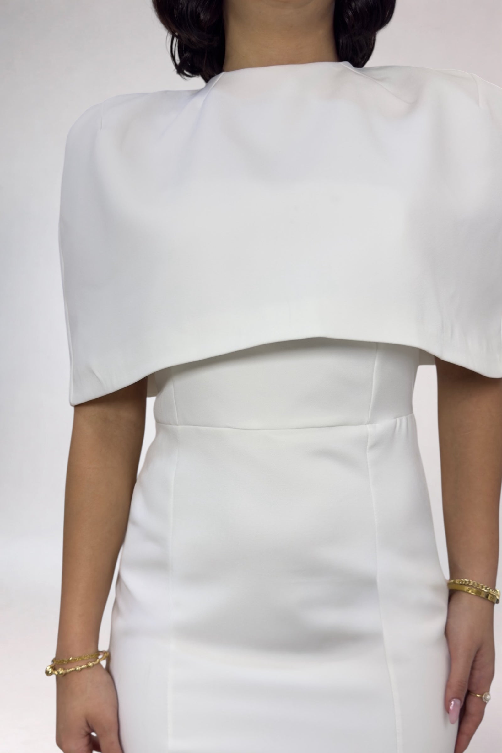 White dress with a draped neckline on a plain background