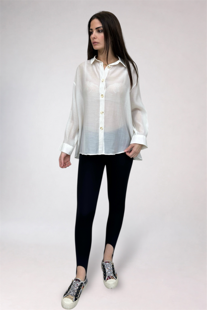 Woman wearing a white shirt, black leggings, and patterned shoes on a plain background