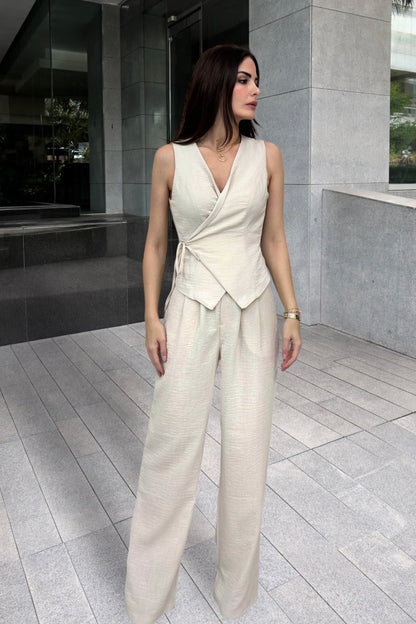 Woman wearing a white sleeveless top and wide-leg pants standing in an urban setting.