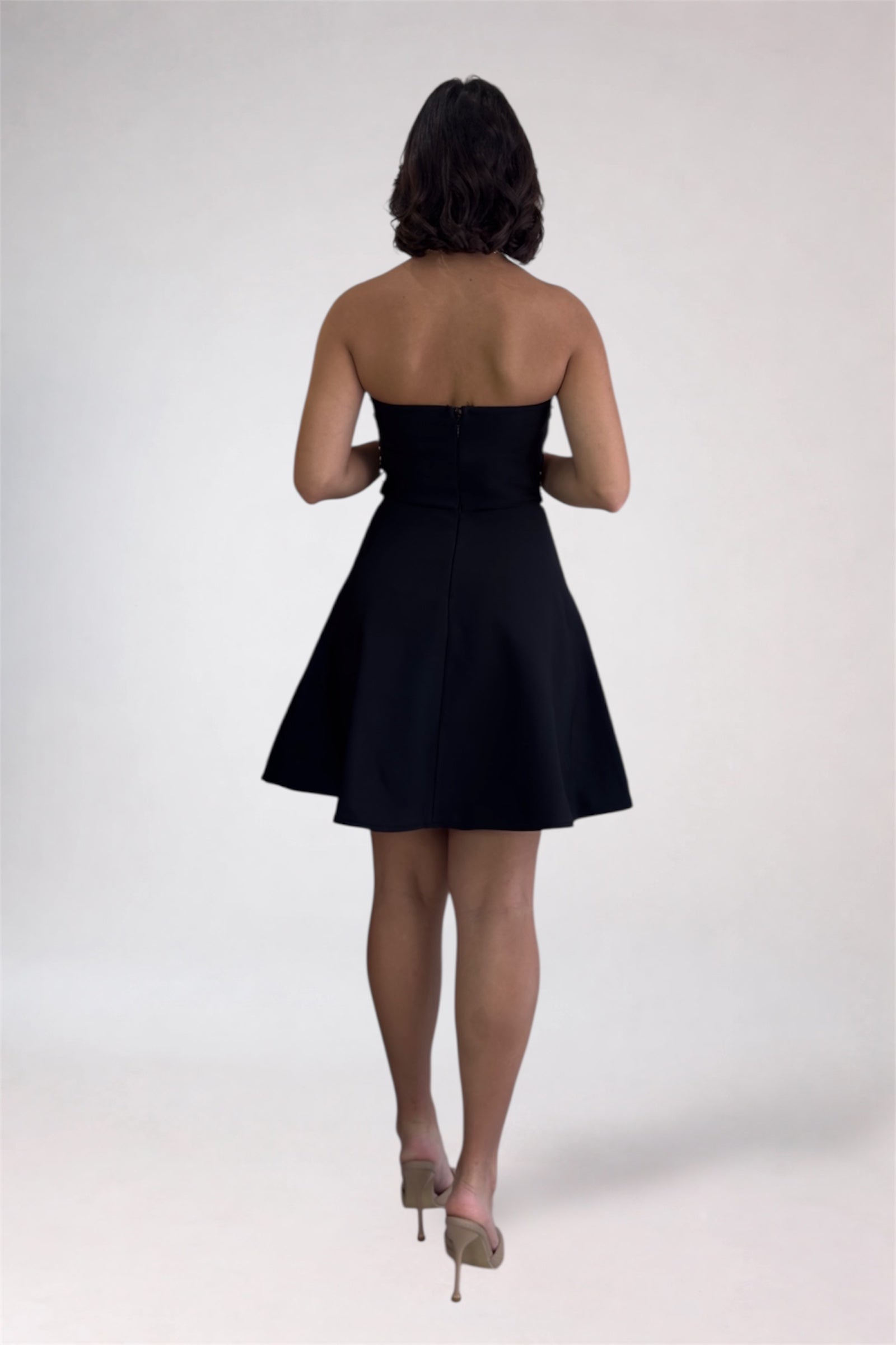 Woman wearing a black strapless dress on a white background