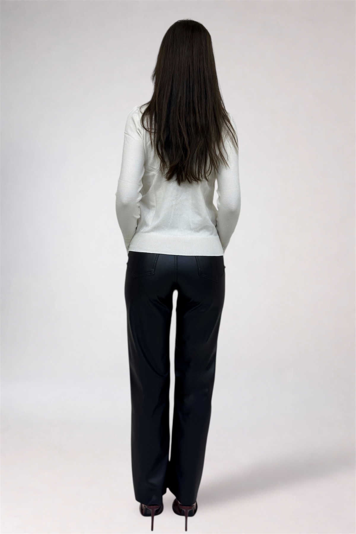 Person wearing a white blouse and black pants on a plain background