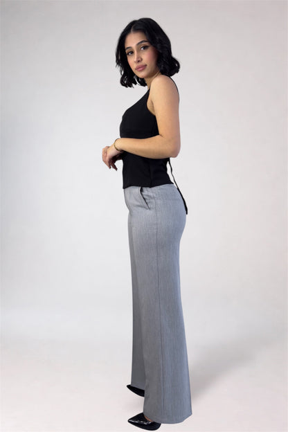 Woman wearing a black top and gray wide-leg pants on a white background