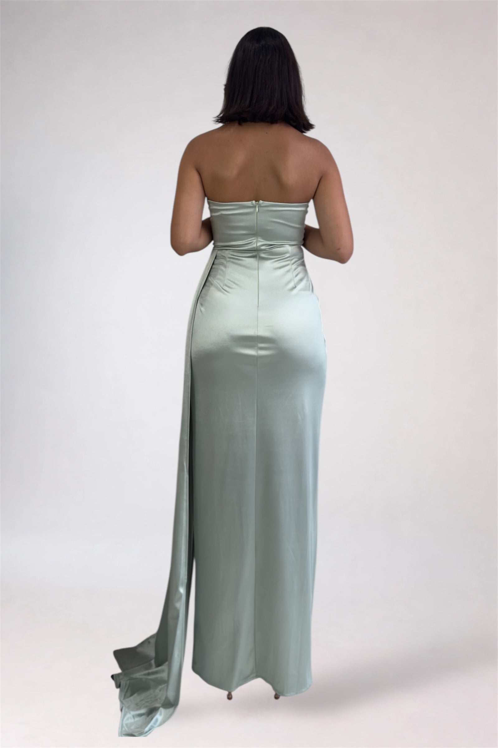 Woman wearing a strapless, floor-length light blue dress on a white background