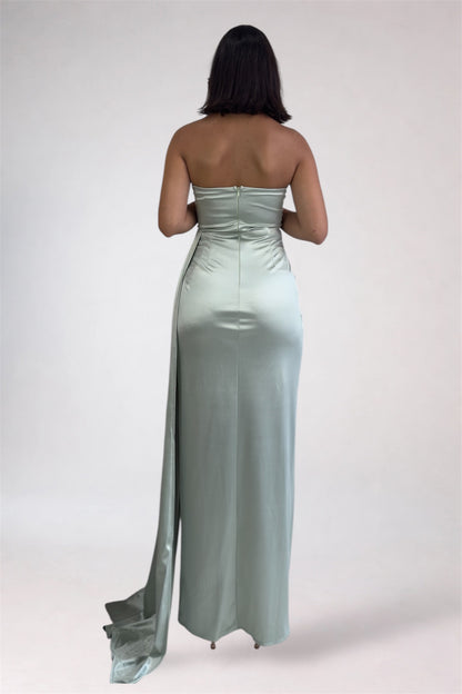 Woman wearing a strapless, floor-length light blue dress on a white background