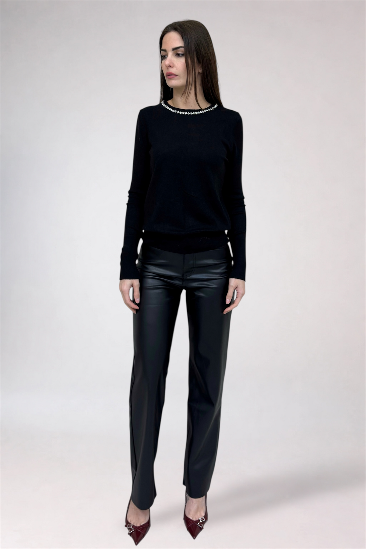 Woman wearing a black sweater and leather pants on a white background