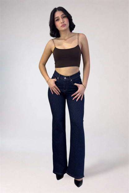 Woman wearing a brown tank top and blue jeans on a white background