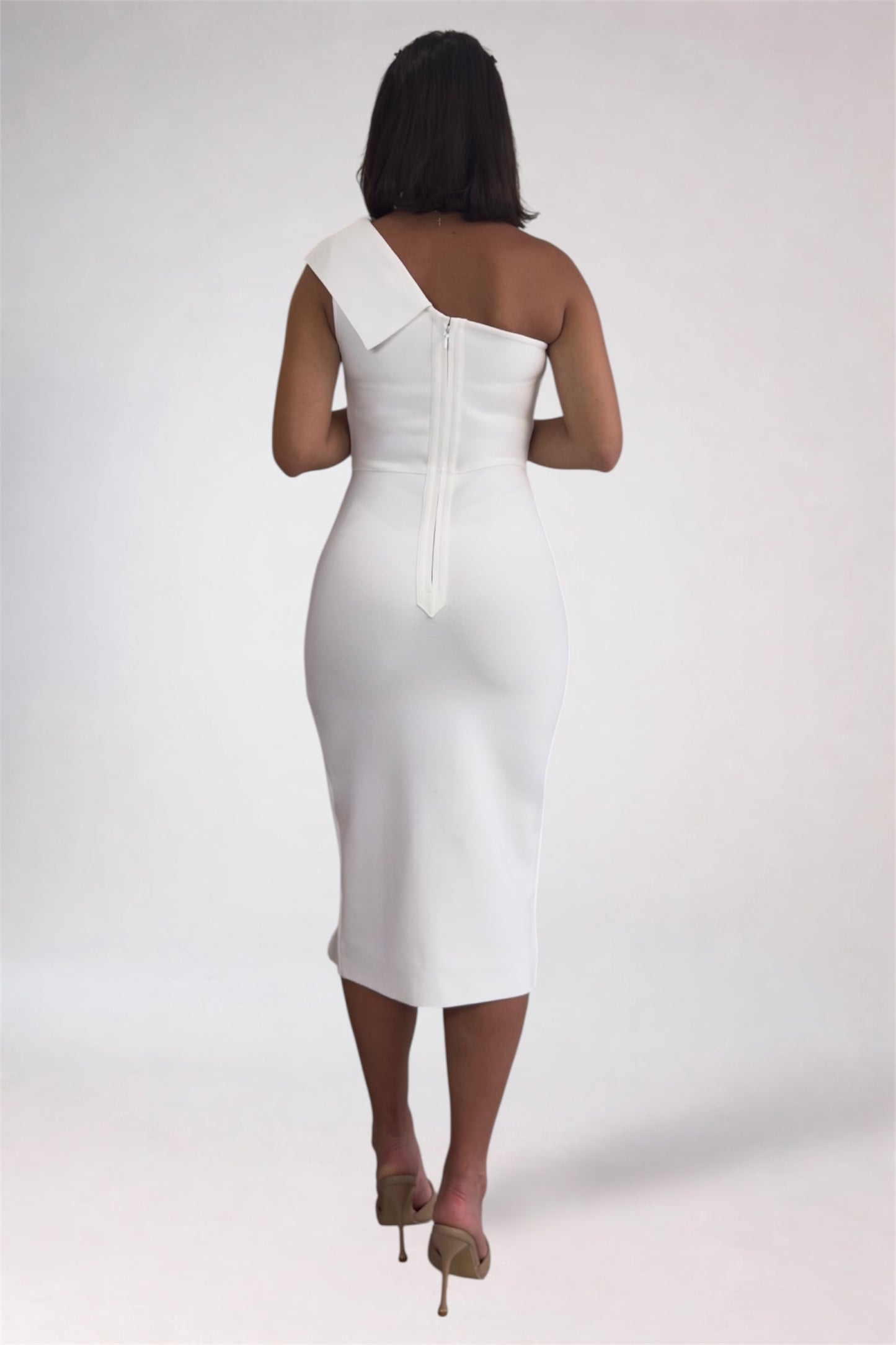 Woman wearing a white one-shoulder dress on a plain background