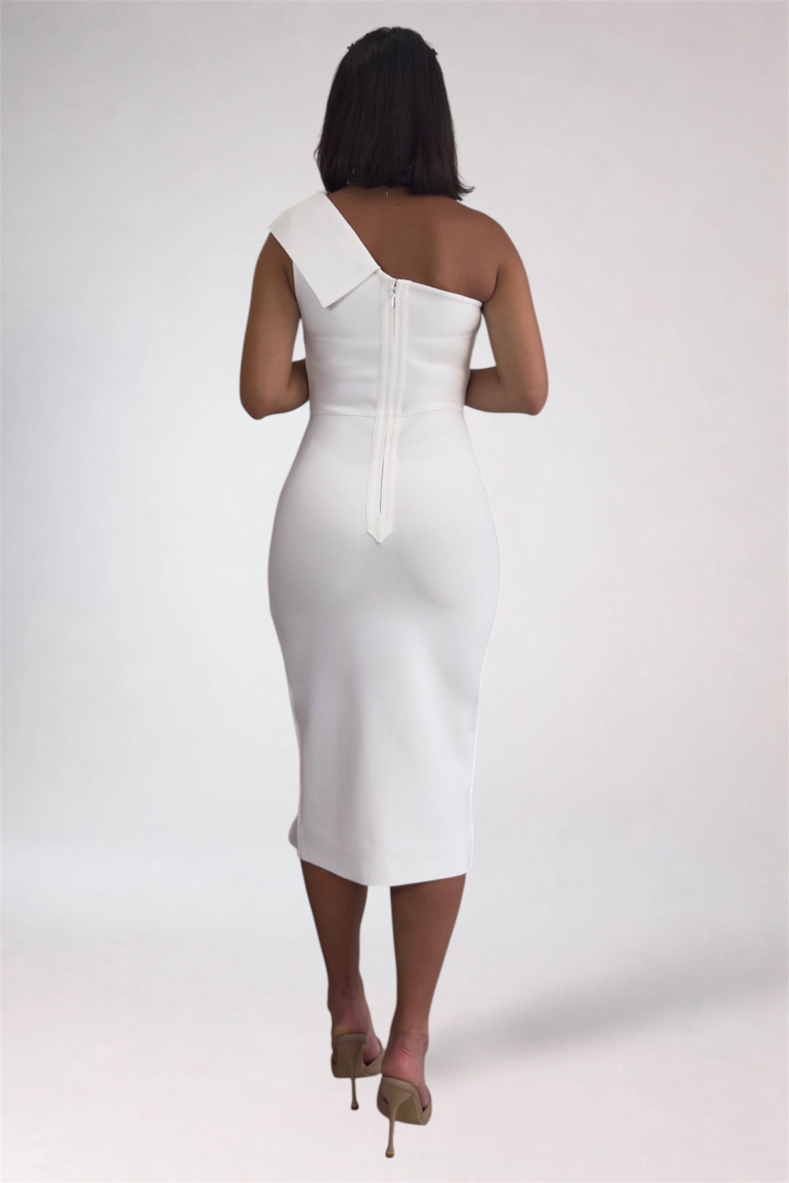 Woman wearing a white one-shoulder dress on a plain background