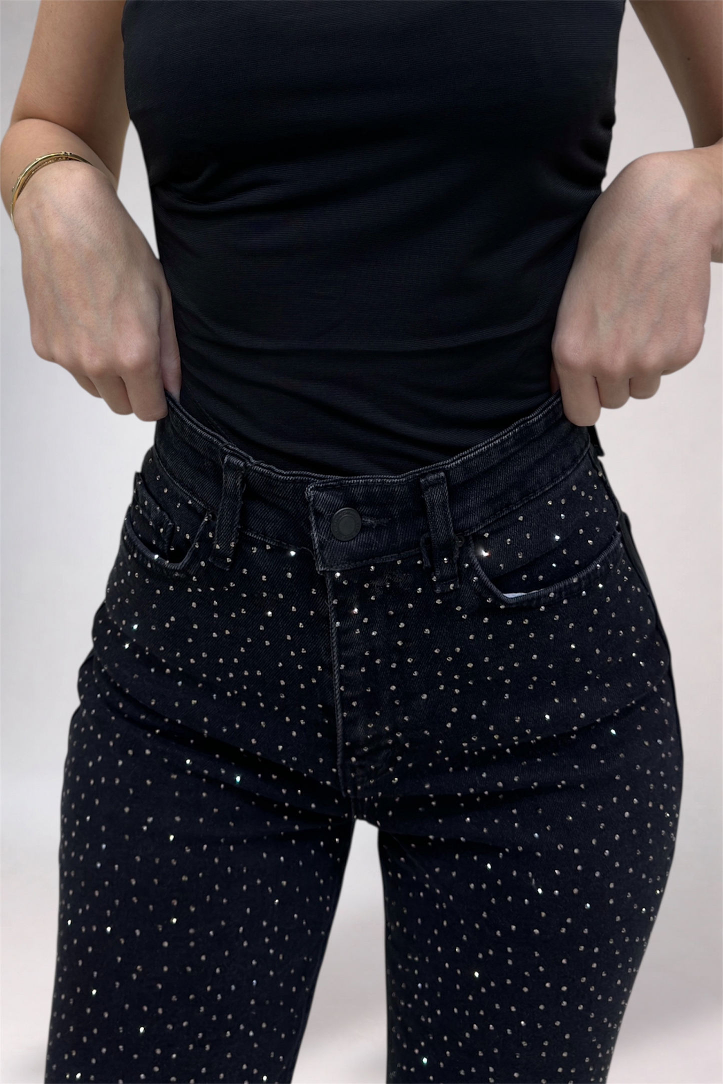 Person wearing black polka dot pants and a black top on a light gray background