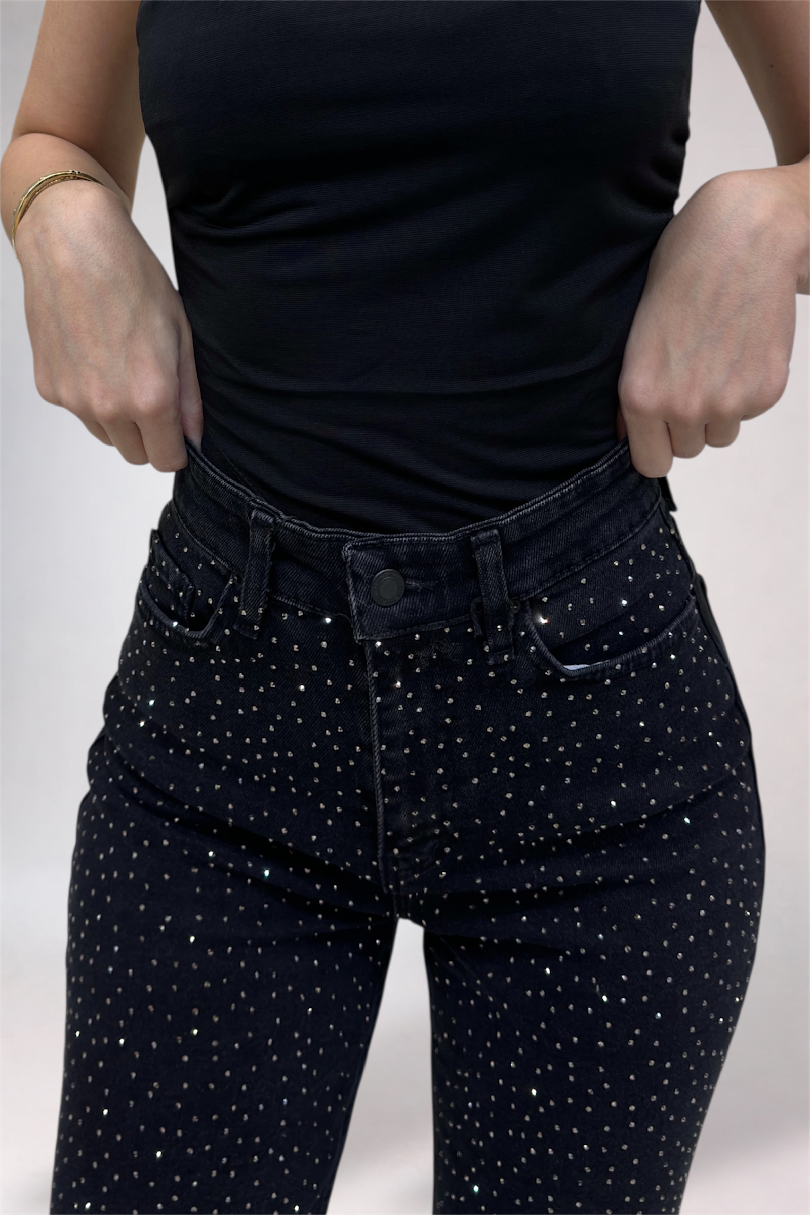 Person wearing black polka dot pants and a black top on a light gray background