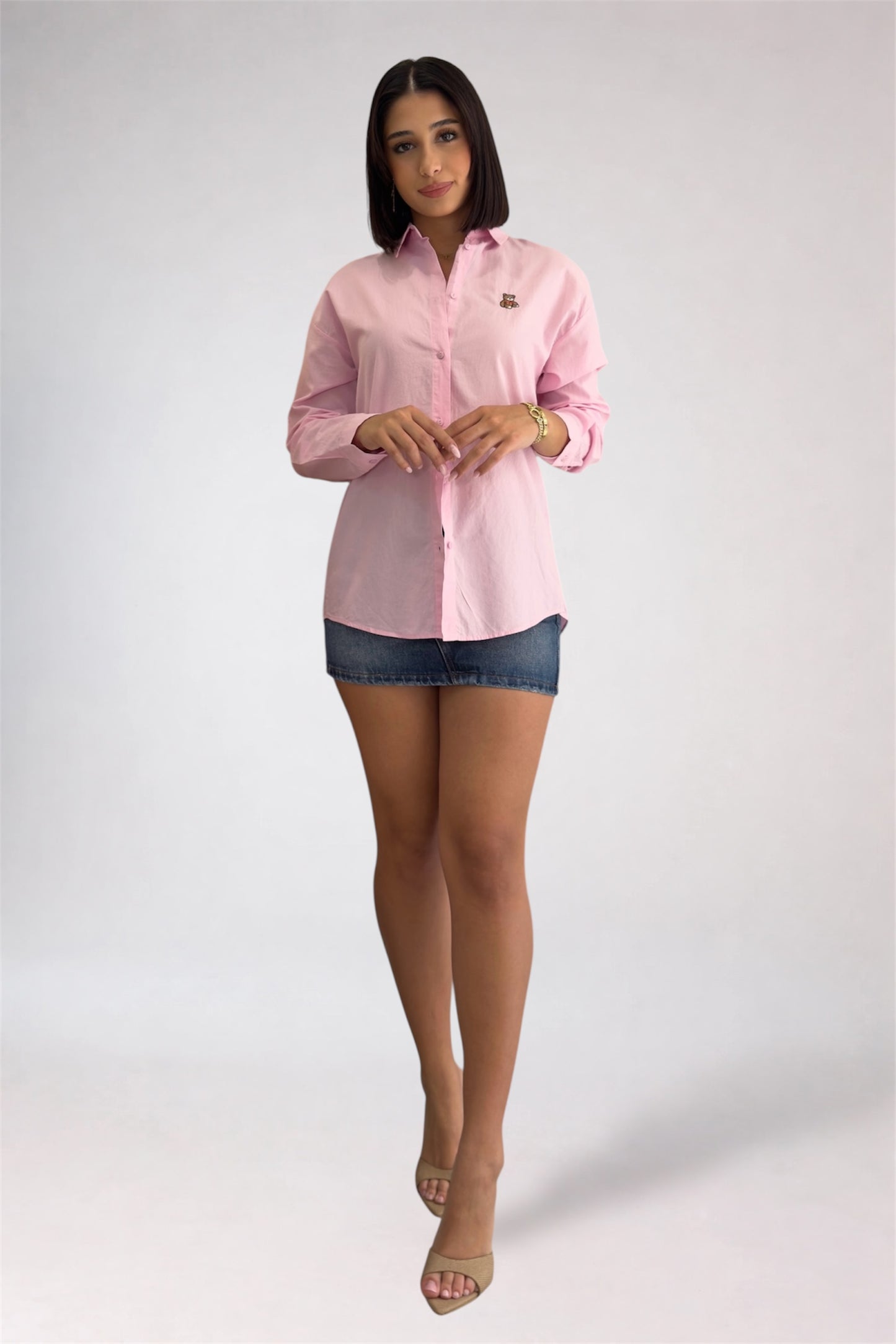 Woman wearing a pink shirt and denim shorts on a white background