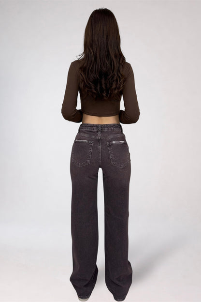 Person wearing dark jeans and a brown long-sleeve top on a white background