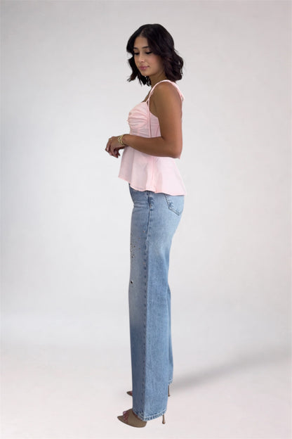 Woman wearing a light pink top and blue jeans on a white background