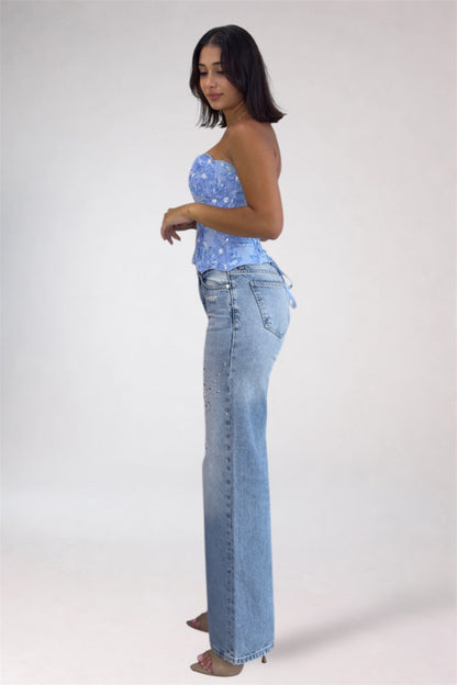 Woman wearing a blue strapless top and light blue jeans on a white background