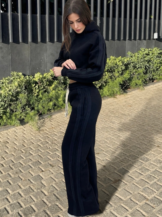 Woman wearing a black outfit standing on a paved path with greenery in the background