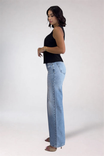 Woman wearing light blue jeans and a black top on a white background